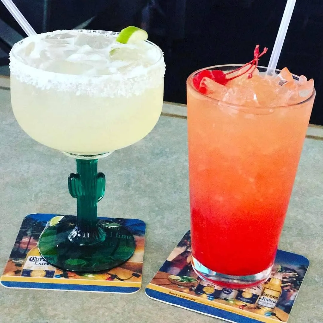 A salt-rimmed margarita and a tequila sunrise on the bar